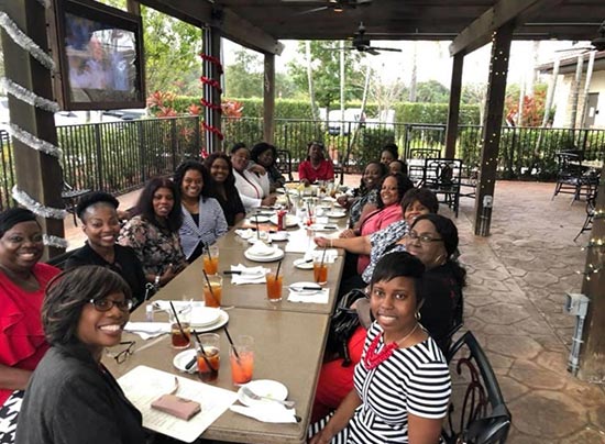 large group of women sitting at a restaurant and smiling