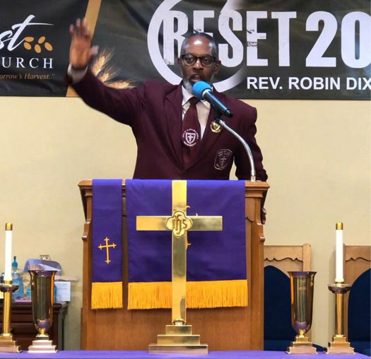 preacher with arm raised speaking into a microphone at a lectern