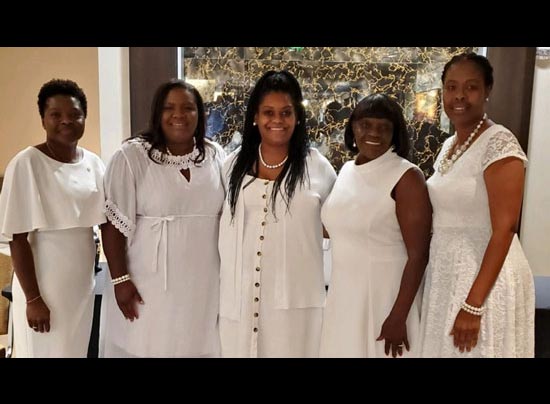 five women dressed in white smiling at the camera